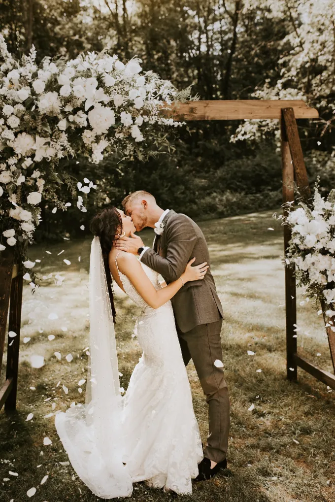 kiss underneth the outdoor ceremony arch